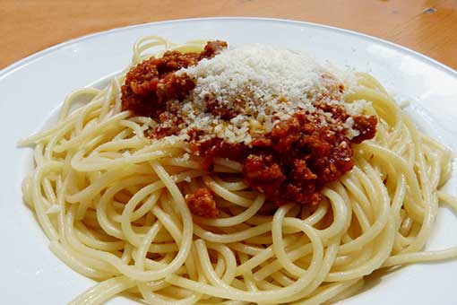 A plate of spaghetti with meat sauce and parmesan cheese.